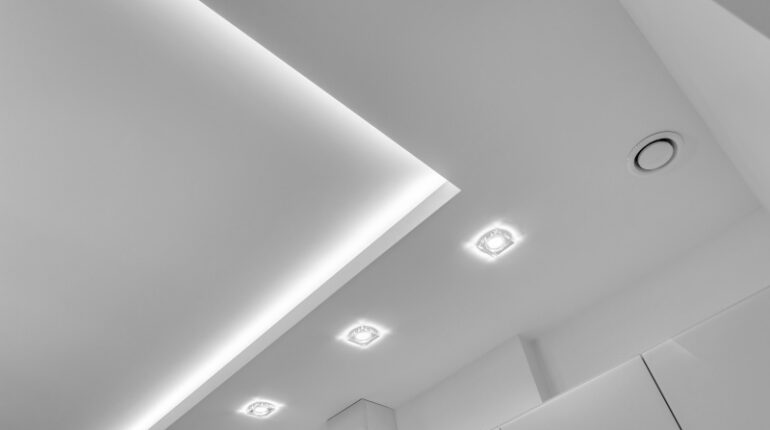 Najlepsze rodzaje oświetlenia salonu według architektów: lampa sufitowa z listwami LED versus halogeny